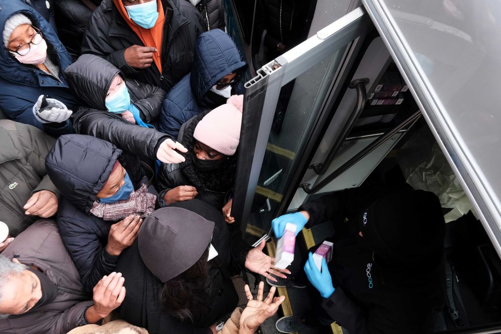People form a large crowd as they attempt to receive COVID-19 testing kits from city workers distributing the kits along Flatbush Avenue in Brooklyn on Dec. 24, 2021