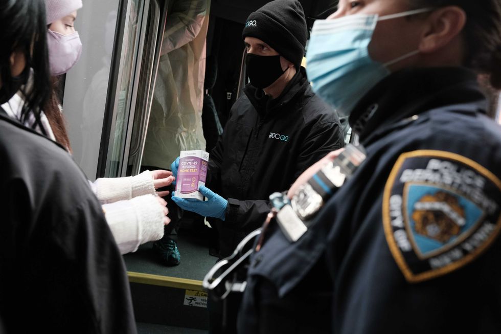 People form a large crowd as they attempt to receive COVID-19 testing kits from city workers distributing the kits along Flatbush Avenue in Brooklyn on Dec. 24, 2021
