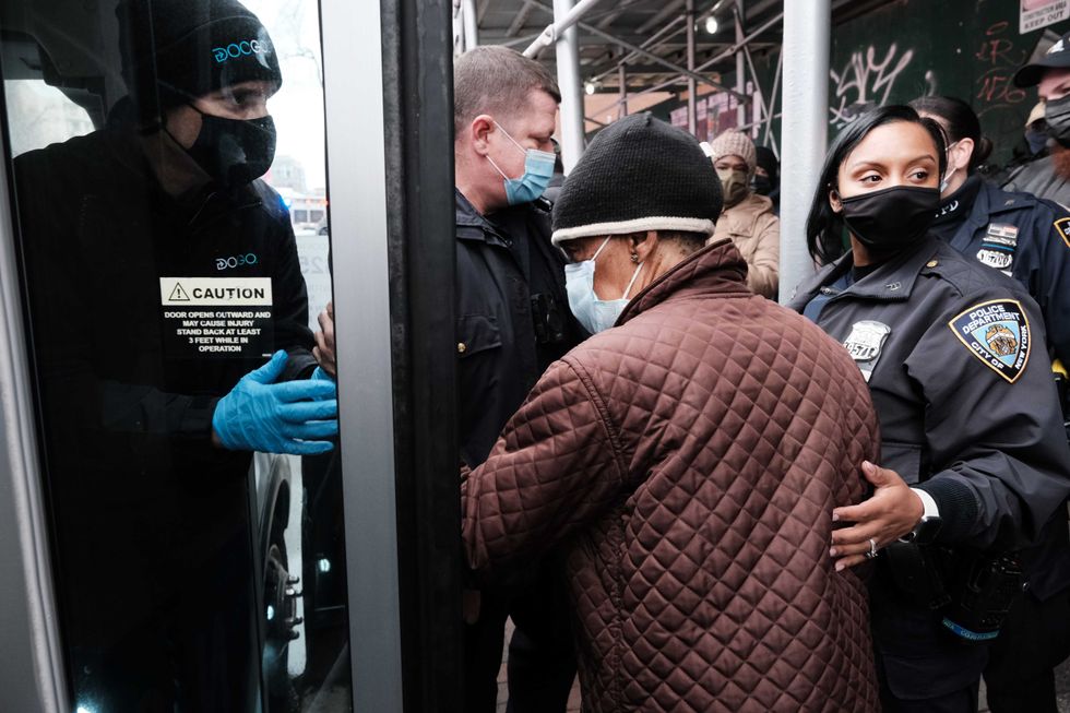 People form a large crowd as they attempt to receive COVID-19 testing kits from city workers distributing the kits along Flatbush Avenue in Brooklyn on Dec. 24, 2021