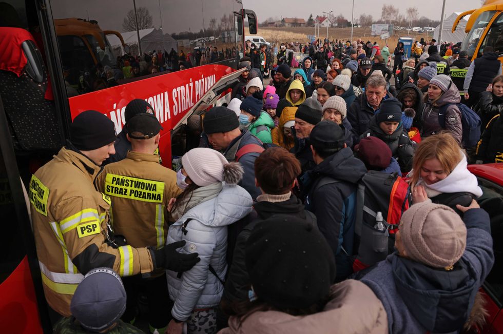 People from war-torn Ukraine wait to board a bus that will take them to nearby Przemysl shortly after their arrival in Poland at the Medyka border crossing on March 04, 2022 near Medyka, Poland