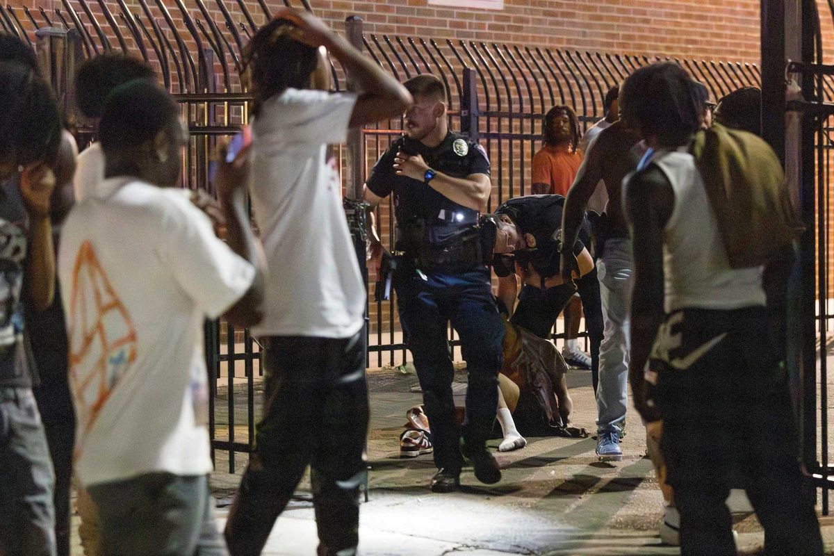 People gather around as police attend to a person after gun shots were fired during a high school football game between Del City and Choctaw in Choctaw, Okla. on Friday, Aug. 25, 2023.