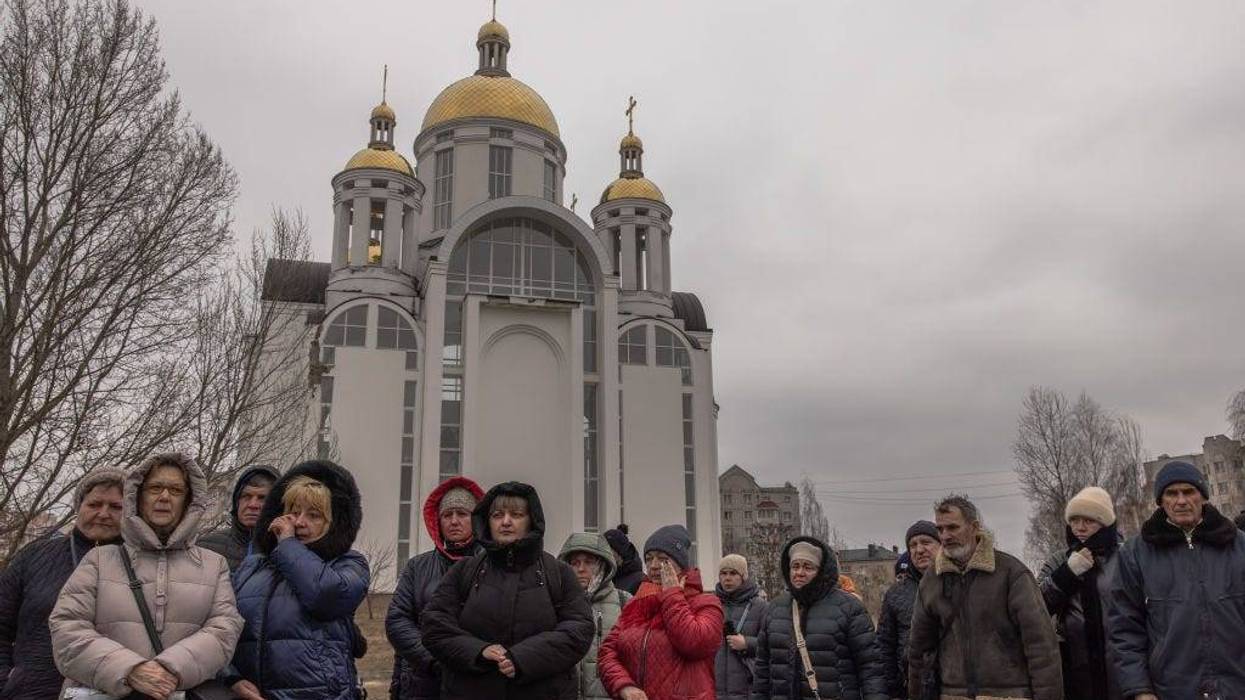 People gather at a site where a mass grave was discovered in front of the church of Saint Andrew Pervozvannoho All Saints, as Ukraine marks one year since Russia's large-scale invasion, on February 24, 2023 in Bucha, Ukraine.