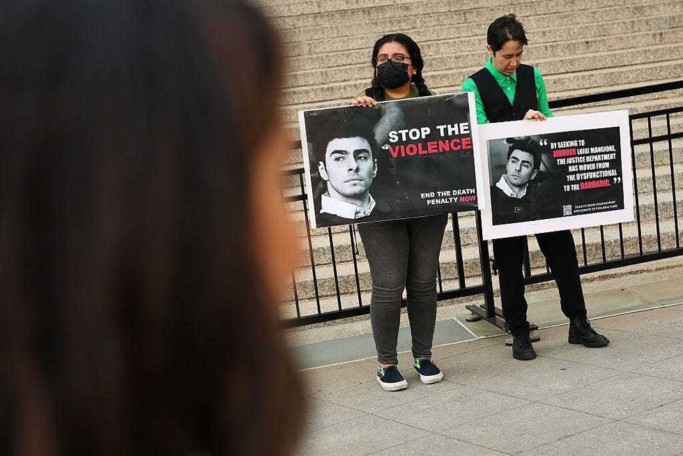 People hold signs in front of Federal Court ahead of an arraignment hearing for Luigi Mangione, accused gunman in the killing of UnitedHealthcare CEO Brian Thompson, on April 25, 2025 in New York City.