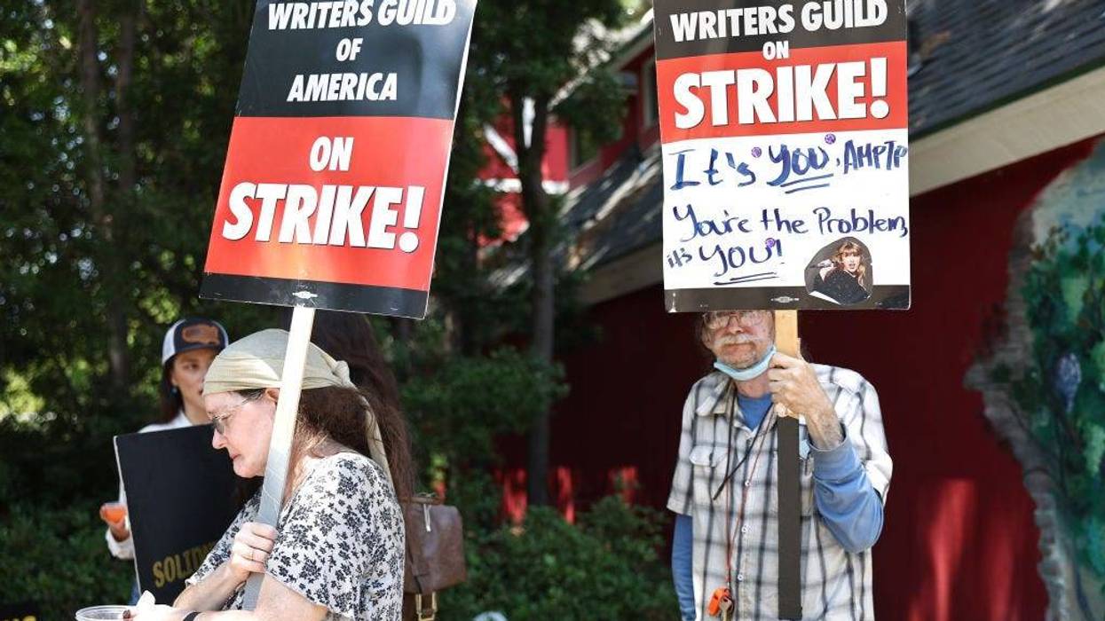 People hold signs in support of striking WGA (Writers Guild of America) members on Day 5 outside Warner Bros. Studio on July 17, 2023 in Burbank, California.