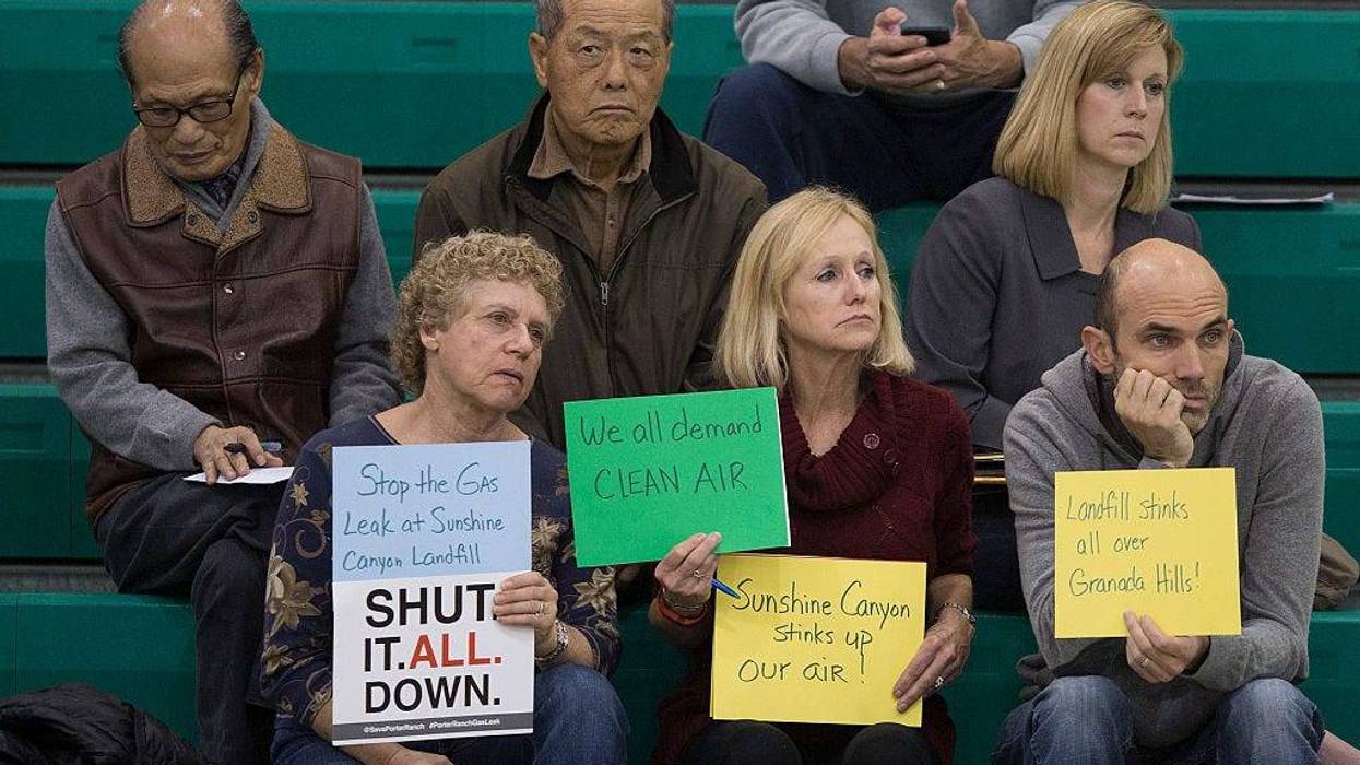 People hold signs while attending a public hearing before the South Coast Air Quality Management District (AQMD) regarding a proposed stipulated abatement order to stop a nearby massive natural gas leak, on January 16, 2016 in Granada Hills, near Porter Ranch, California.