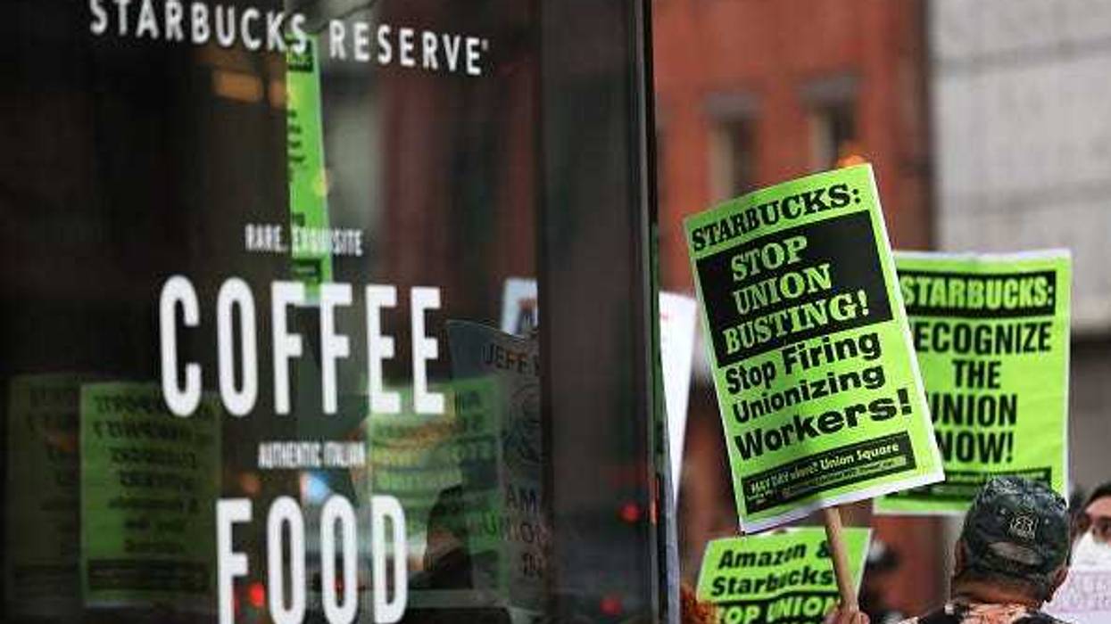 People hold signs while protesting in front of Starbucks on April 14, 2022 in New York City. Activists gathered to protest Starbucks' CEO Howard Schultz anti-unionization efforts and demand the reinstatement of workers fired for trying to unionize.