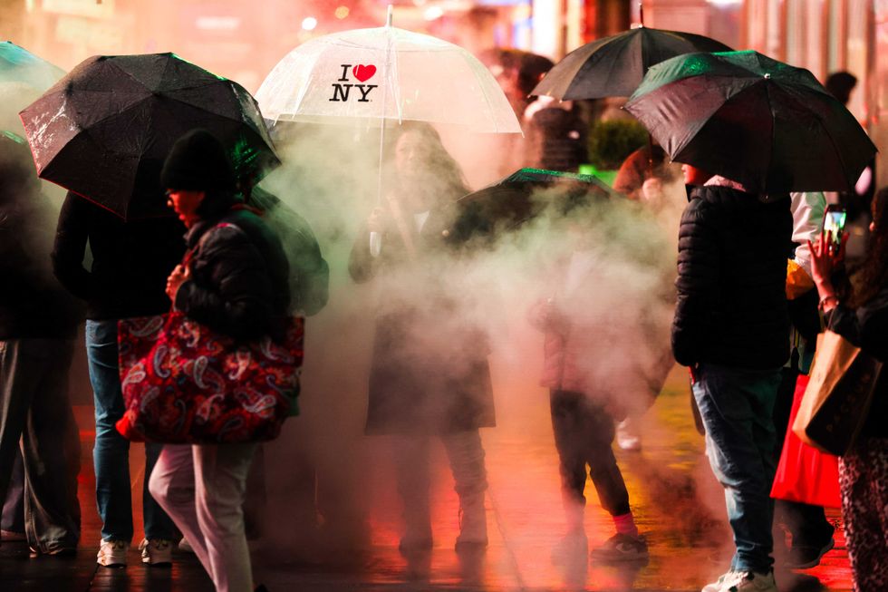 People hold umbrellas as they walk through Times Square on Nov. 22, 2024