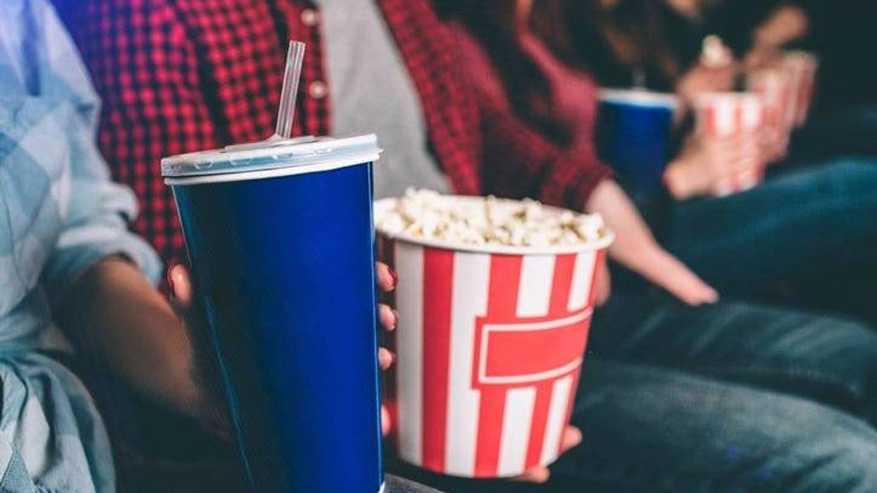 People holding popcorn and drinks in a movie theater.