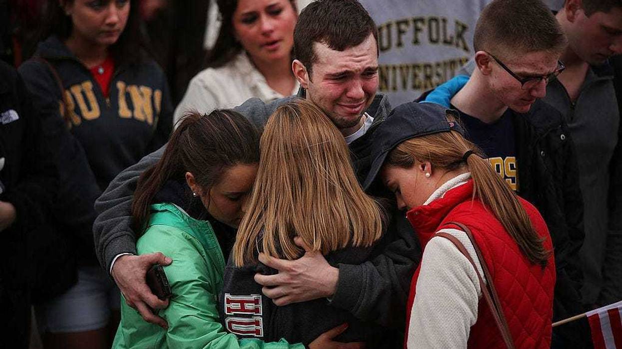 People hug and cry during a vigil for victims of the Boston Marathon bombings at Boston Commons on April 16, 2013 in Boston, Massachusetts. The twin bombings, which occurred near the marathon finish line, resulted in the deaths of three people while hospitalizing at least 140. The bombings at the 116-year-old Boston race, resulted in heightened security across the nation with cancellations of many professional sporting events as authorities search for a motive to the violence. (Photo by Spencer Platt/Getty Images)