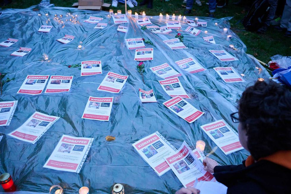 People lay on the ground sheets of paper with missing persons notices of people who were abducted during Hamas