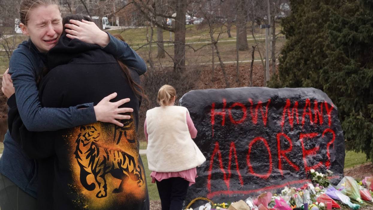 People leave flowers, mourn and pray at a makeshift memorial at "The Rock" on the campus of Michigan State University on February 14, 2023 in East Lansing, Michigan. A gunman opened fire at two locations on the campus Monday night, killing three students and injuring several others.