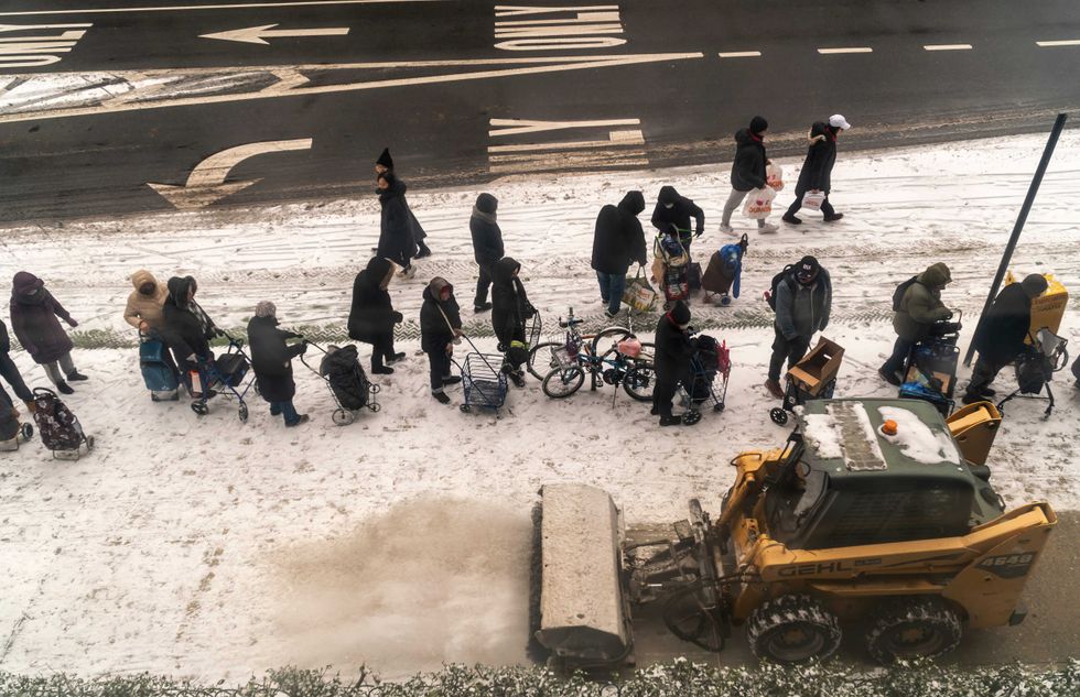 People line up in the snow for clothing and blankets at the Church of the Holy Apostles in Chelsea on Dec. 24, 2024