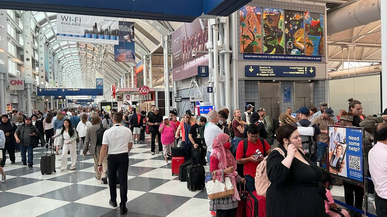 People lining up to check in at crowded/reissued tickets at Chicago O'Hare Airport.