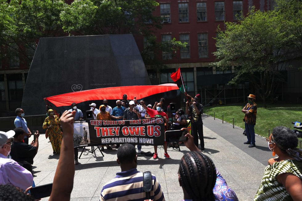 People listen to speakers during a rally for reparations at the African Burial Ground National Monument in Lower Manhattan on July 23, 2021