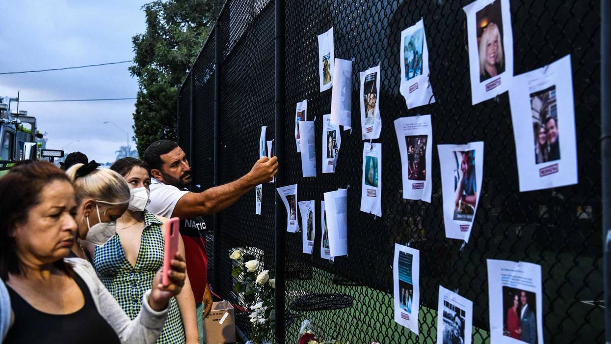 People look at pictures of missing residents of the partially collapsed building at a makeshift memorial in Surfside, north of Miami Beach, on June 25, 2021. - Four people were confirmed dead and 159 unaccounted for Friday following the collapse of an oceanfront apartment building near Miami Beach, as rescue teams scoured a mountain of rubble in a desperate search for survivors