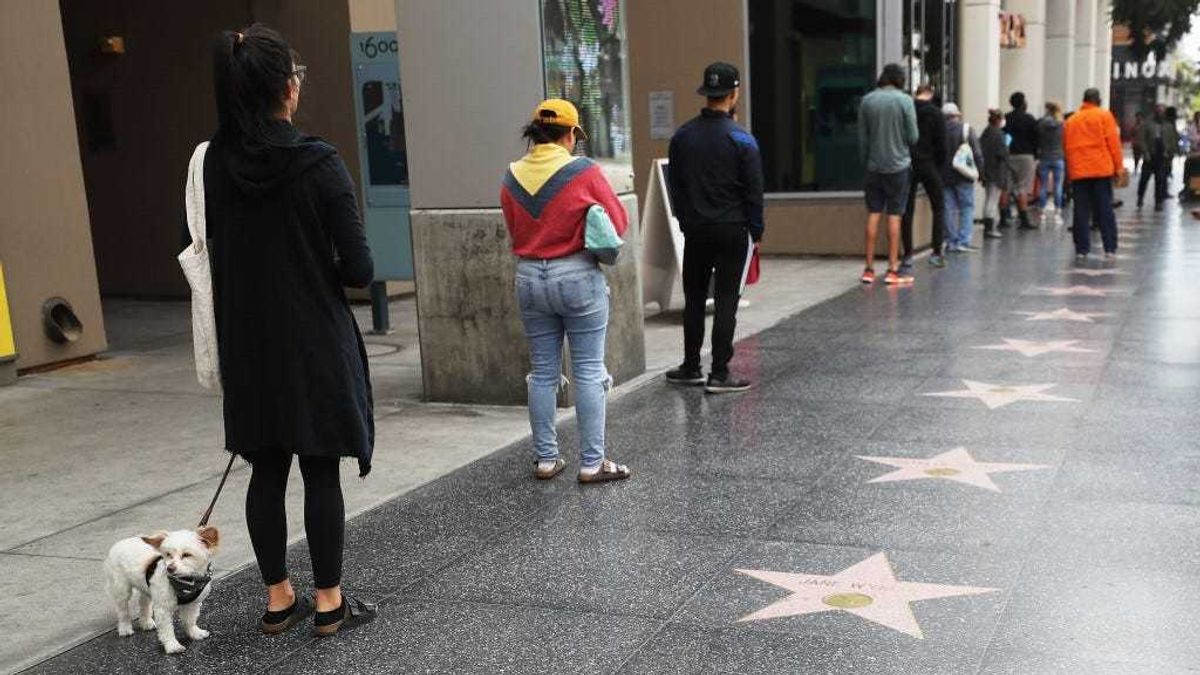 People maintain social distancing while standing in line to enter a Trader Joe's, along the Hollywood Walk of Fame, as the coronavirus pandemic continues on March 25, 2020 in Los Angeles, California.
