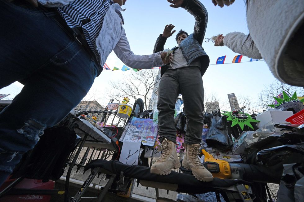 People pay a vendor selling trinkets on the Manhattan side of the Brooklyn Bridge on Jan. 1, 2024