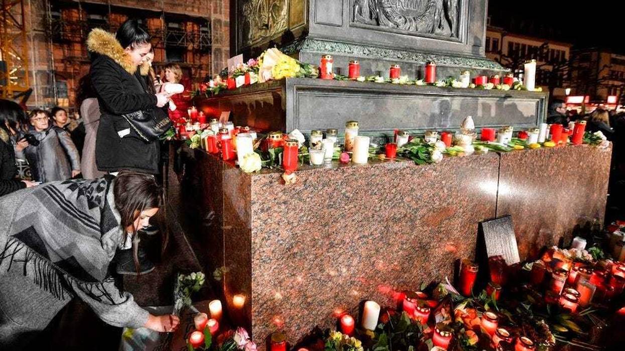 People place candles and flowers at a monument on the market place during a mourning for the victims of the shooting in Hanau, Germany, Thursday, Feb. 20, 2020. (AP Photo/Martin Meissner)