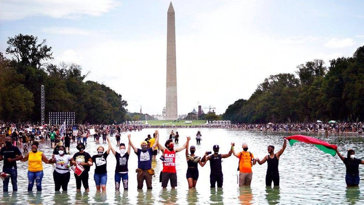 People pose for a group photo in the Reflecting Pool in the shadow of the Washington Monument as they attend the March on Washington (AP)