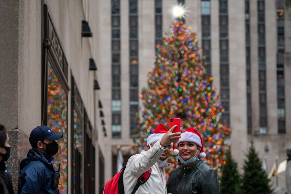 People pose for a selfie at the Rockefeller Christmas Tree on December 25, 2020 in New York City. People are celebrating Christmas during the pandemic as the city reports an increase of nearly 2,900 new cases and a 7 day positivity rate of 6.29%.