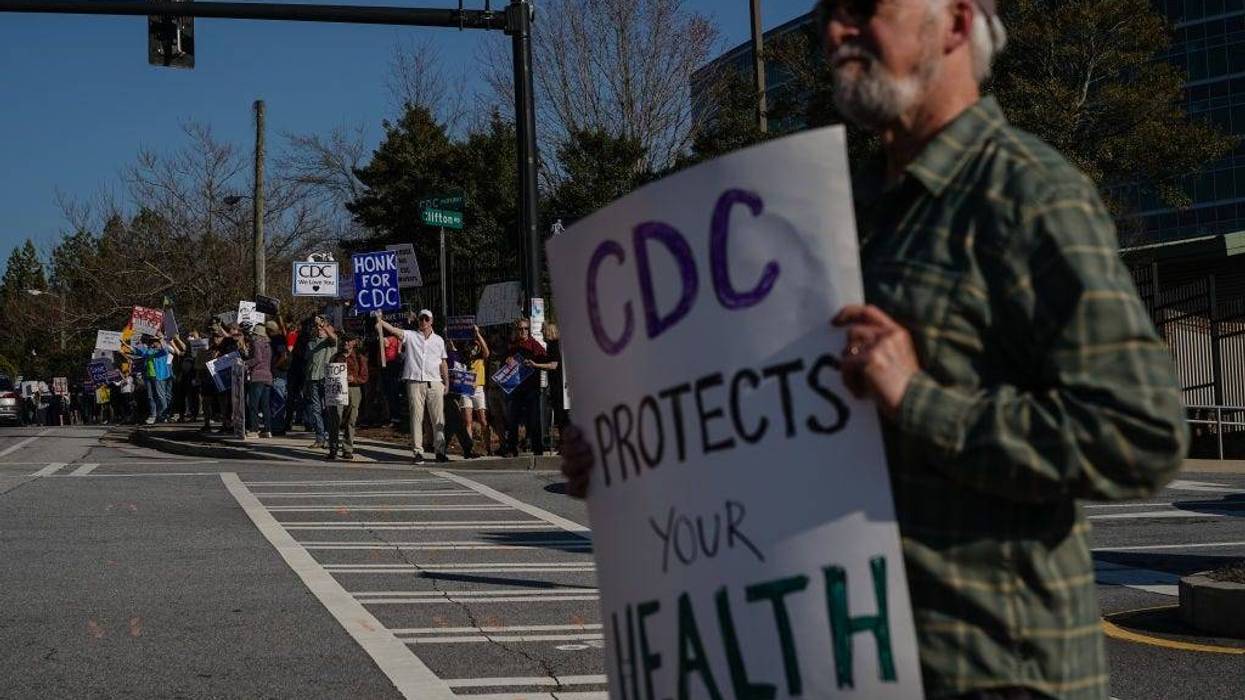 People protesting personnel cuts at the Centers for Disease Control (CDC) hold signs outside the organization's main headquarters on March 12, 2025 in Atlanta, Georgia.
