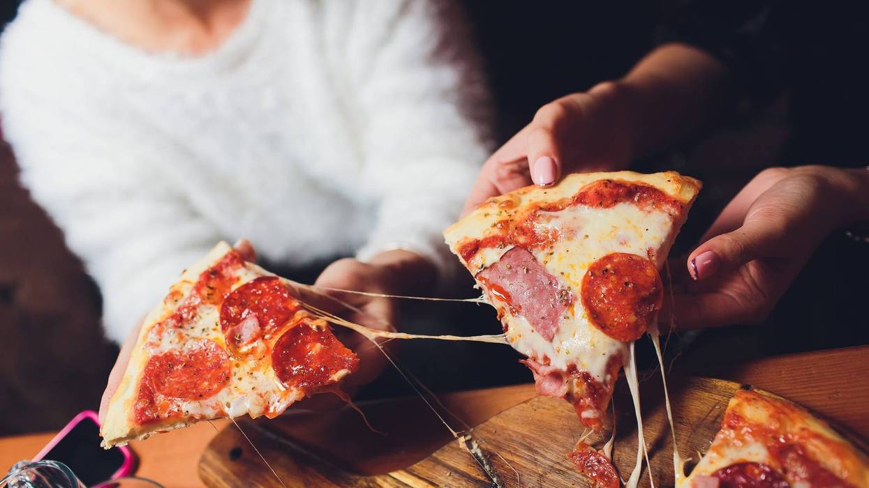 People pulling out two slices of pizza