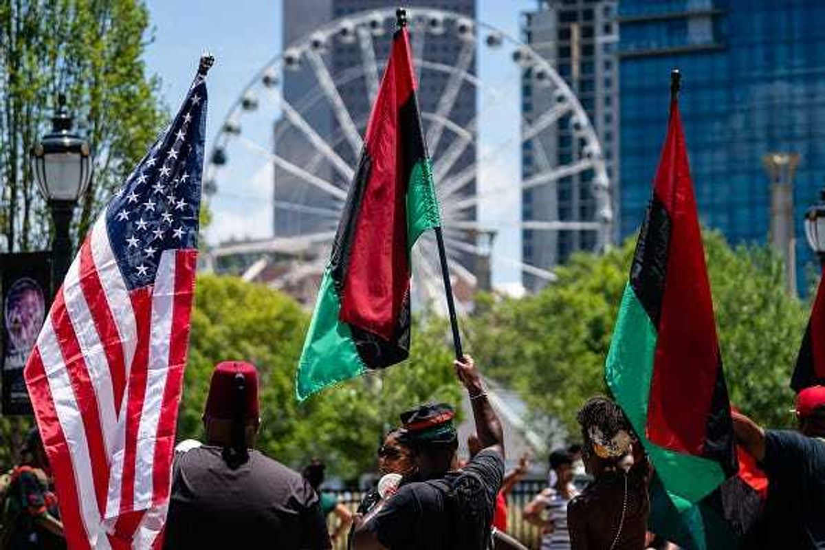 People raise American and Pan-African flags while marching in the Juneteenth Atlanta Black History parade on June 18, 2022 in Atlanta, United States.