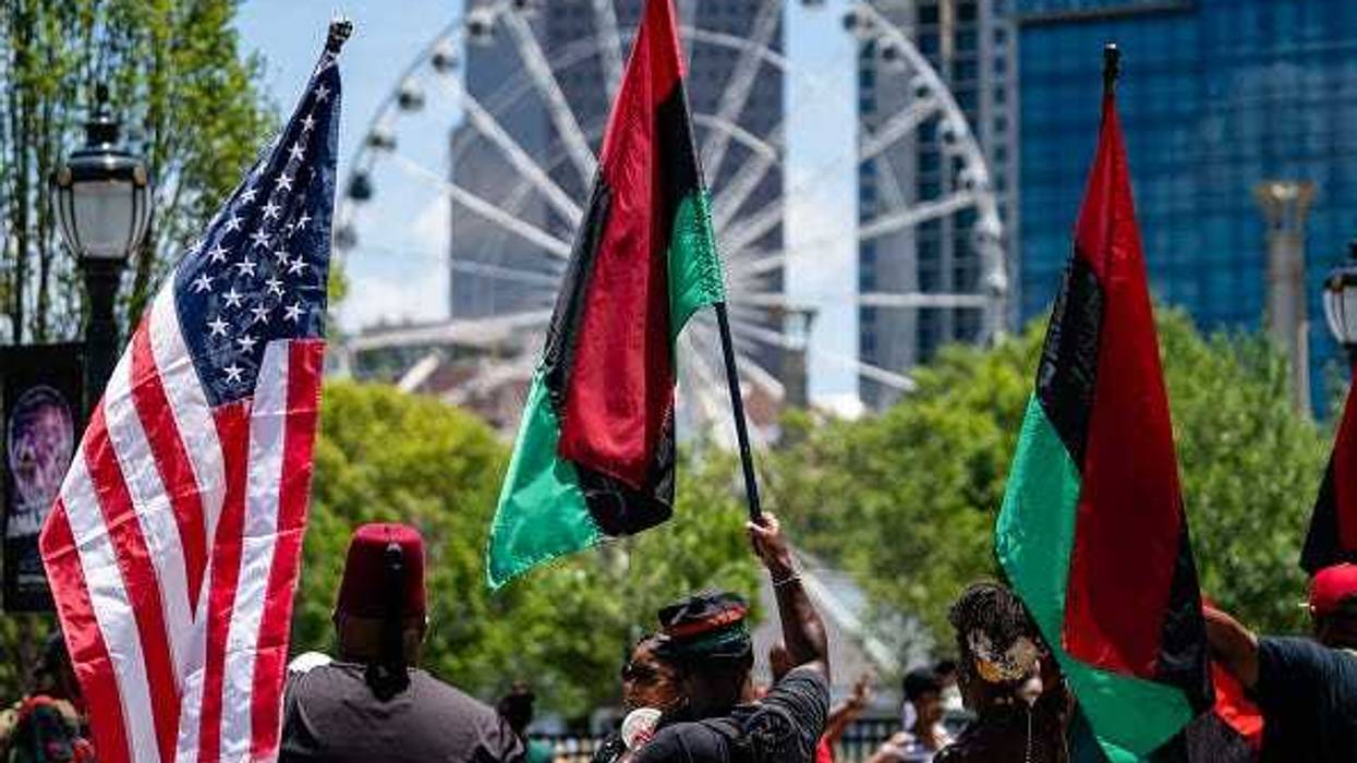 People raise American and Pan-African flags while marching in the Juneteenth Atlanta Black History parade on June 18, 2022 in Atlanta, United States.