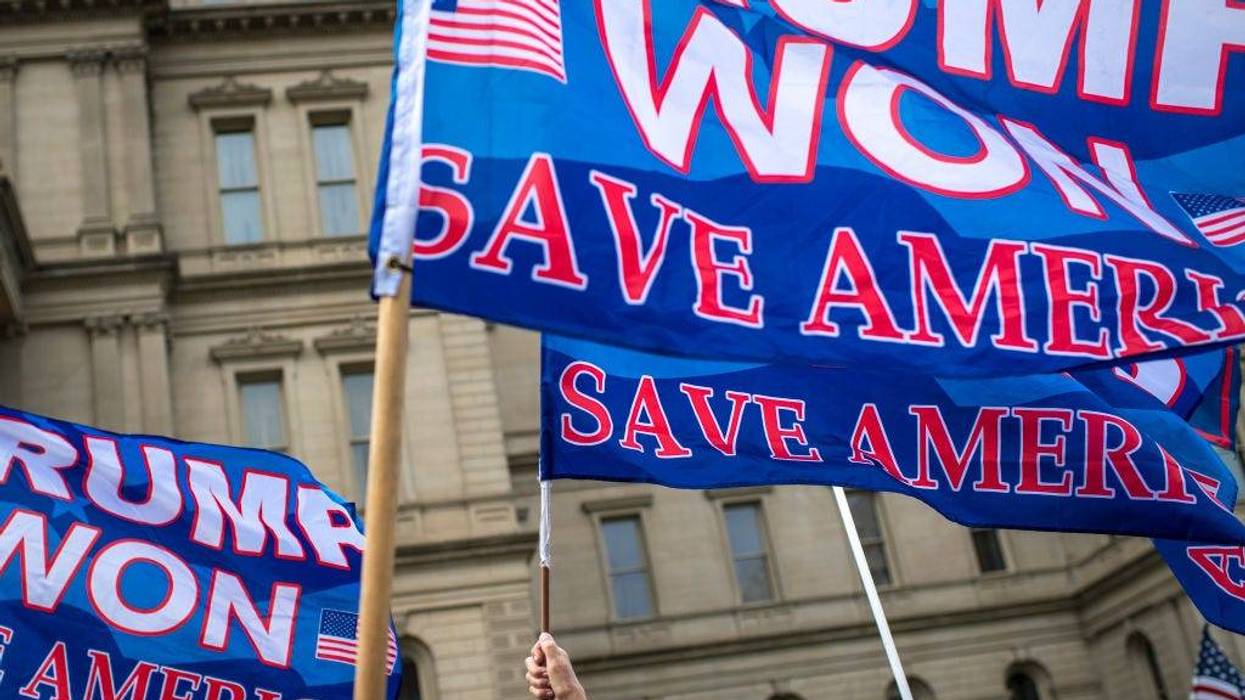 People raise flags in support of Donald Trump in the air at the Michigan State Capitol on October 12, 2021 in Lansing, Michiga