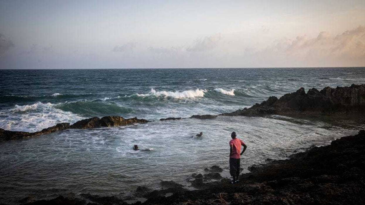 People relax and swim on a secured beach area near the runway of Aden Adde International Airport at sun set on September 4, 2022 in Mogadishu, Somalia. es