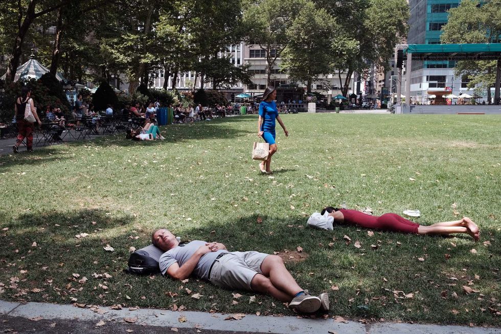People rest in the shade in Bryant Park in midtown Manhattan as temperatures reach into the 90s on July 21, 2022 in New York City