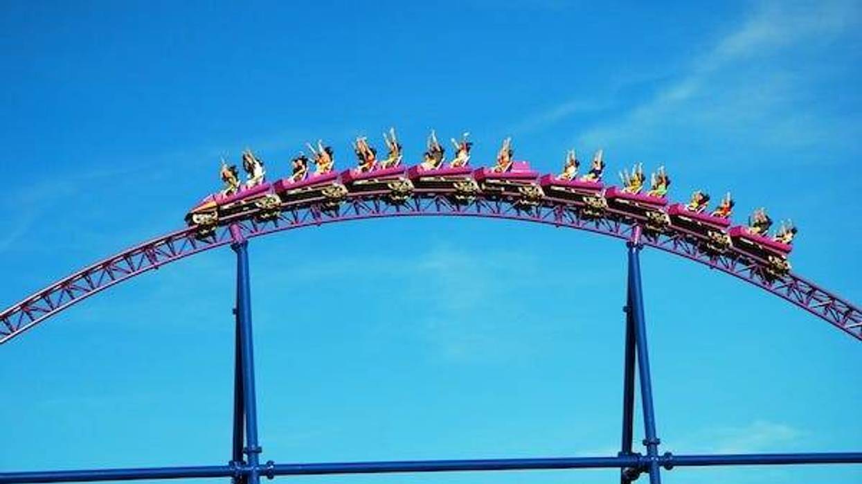 People riding a roller coaster against a blue sky