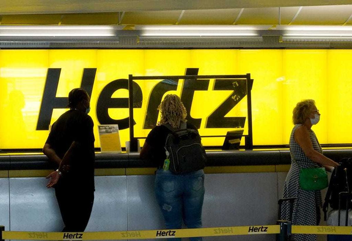 People stand at a Hertz car rental counter in the Fort Lauderdale-Hollywood International Airport on October 25, 2021 in Miami, Florida.