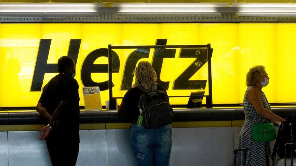 People stand at a Hertz car rental counter in the Fort Lauderdale-Hollywood International Airport on October 25, 2021 in Miami, Florida.