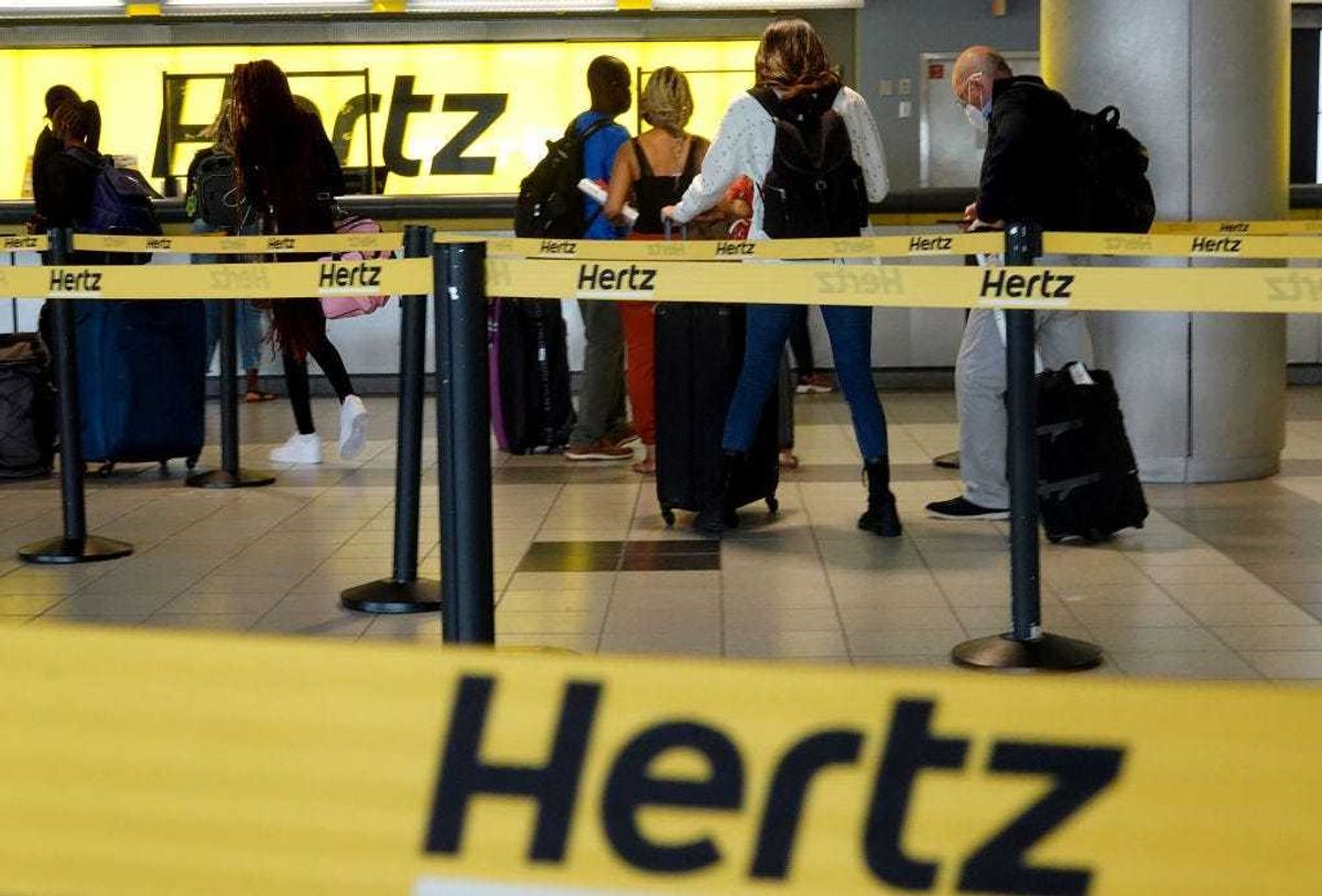 People stand at a Hertz car rental counter in the Fort Lauderdale-Hollywood International Airport on October 25, 2021 in Miami, Florida.