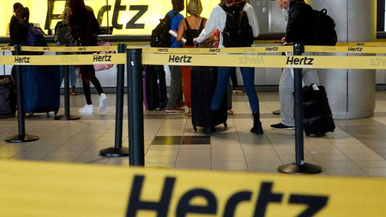 People stand at a Hertz car rental counter in the Fort Lauderdale-Hollywood International Airport on October 25, 2021 in Miami, Florida.