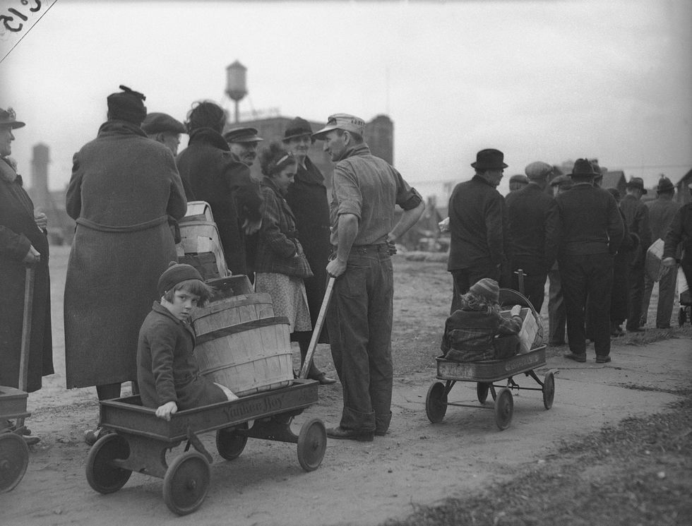 People stand on a breadline, early victims of the Great Depression, as they wait for food on New York
