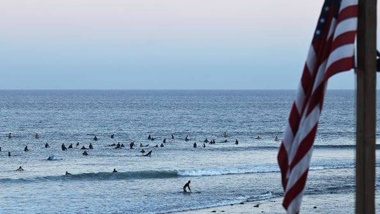 People surf on the Pacific Ocean at a beach located outside the Palisades Fire burn zone on August 26, 2025 in Malibu, California. The U.S. Army Corps of Engineers has begun debris removal at the final “opt-in” property located in the Palisades Fire recovery area with 1,152,714 tons of debris removed from the area during the operation which cleared over 4,000 properties. (Photo by Mario Tama/Getty Images)