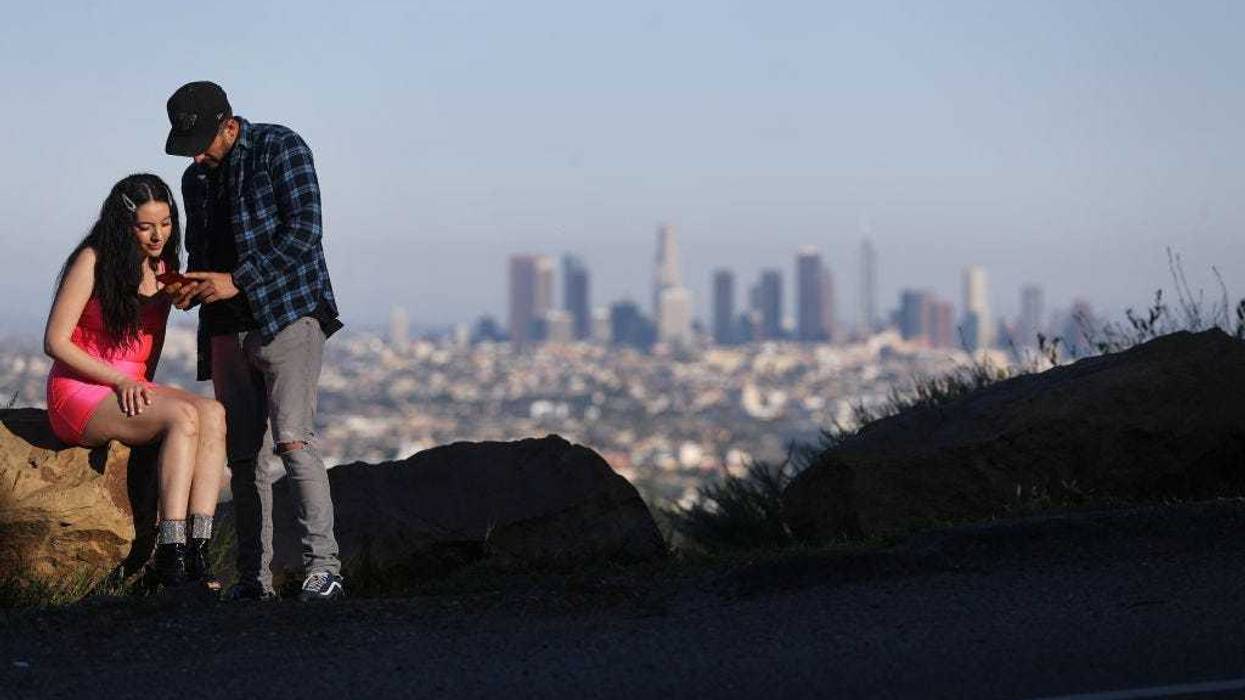 People take photos with downtown visible in the distance in the midst of the coronavirus pandemic on April 15, 2020 in Los Angeles, California. Environmental Protection Agency (EPA) data from March shows that Los Angeles had its longest stretch of air quality rated as "good" since 1995 as Safer-at-Home orders were issued in response to the spread of COVID-19. (Photo by Mario Tama/Getty Images)