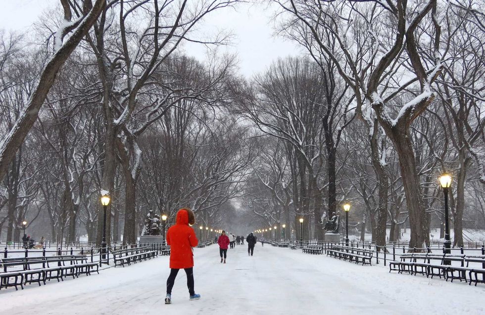 People walk along The Mall as snow falls in Central Park on January 16, 2024