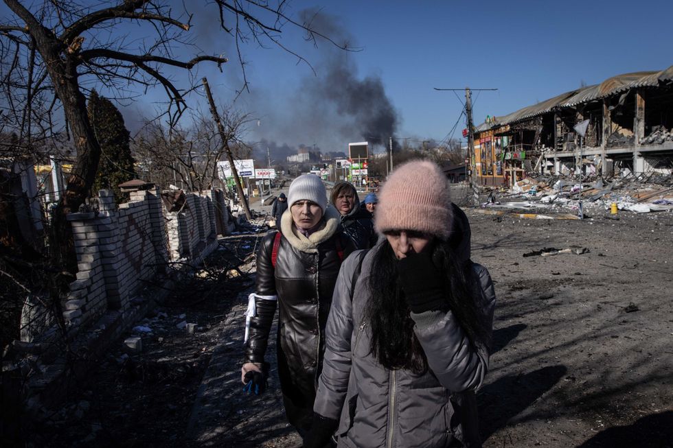 People walk amid destruction as they evacuate from a contested frontline area between Bucha and Irpin on March 10, 2022 in Irpin, Ukraine. Irpin, a suburb northwest of Kyiv, has experienced days of sustained shelling by Russian forces advancing toward the capital