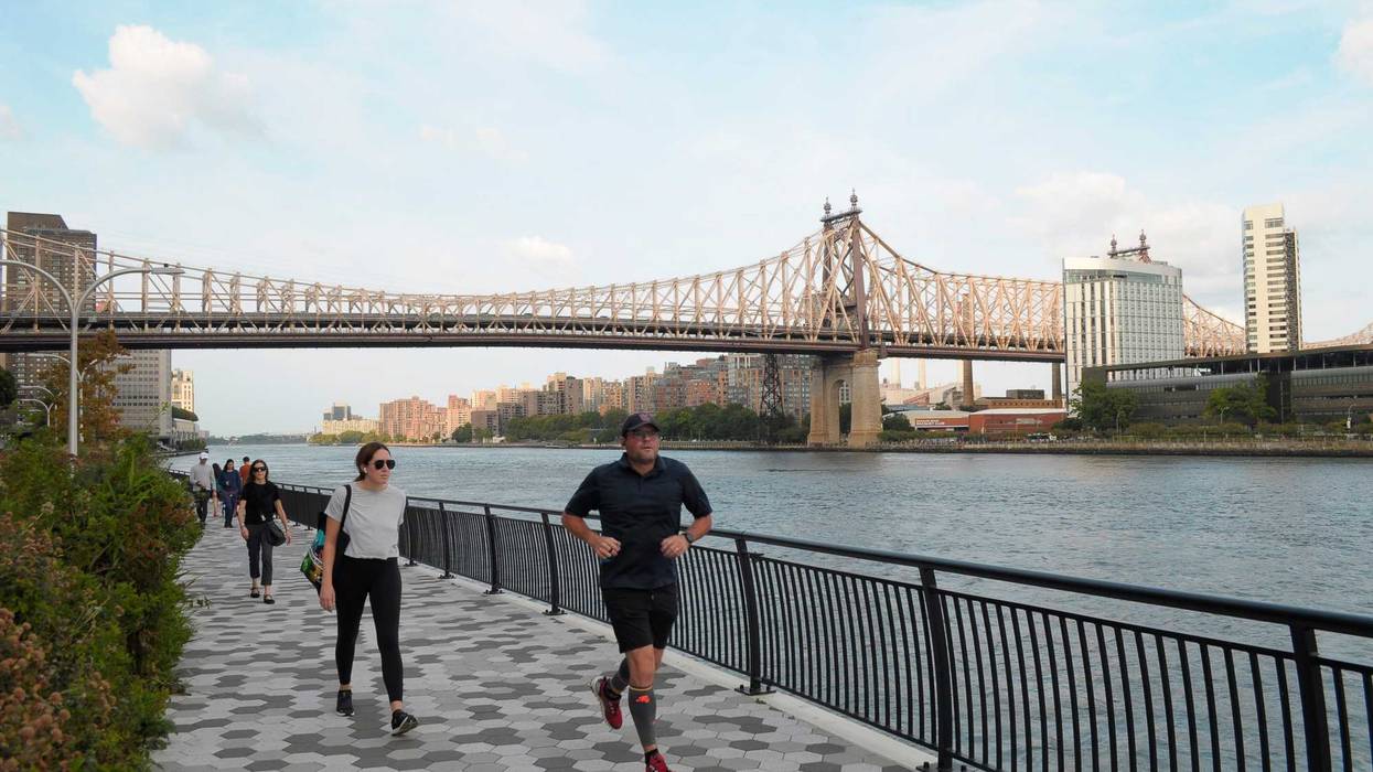People walk and jog on the East River Esplanade also called the East River Greenway in Manhattan