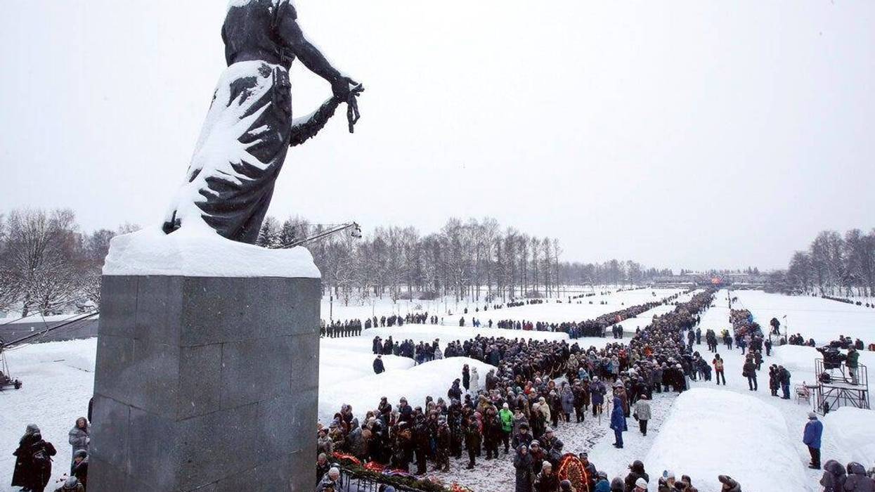 People walk in snowfall to the Motherland monument to put flowers at the Piskaryovskoye Cemetery where most of the Leningrad Siege victims were buried during World War II