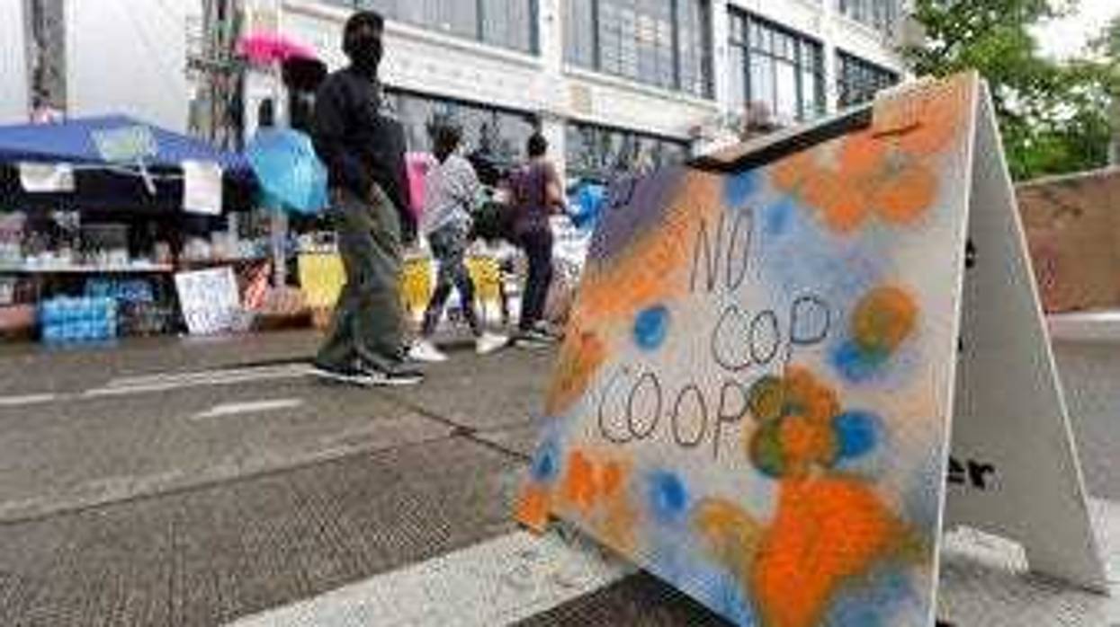 People walk near what is being called the "No Cop Co-op" were protesters and others can get free food and other supplies, Thursday, June 11, 2020, inside what is being called the "Capitol Hill Autonomous Zone" in Seattle. (AP Photo/Ted S. Warren)