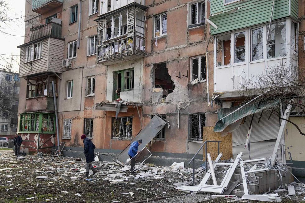 People walk next to an apartment building hit by shelling in Mariupol, Ukraine, Monday, March 7, 2022