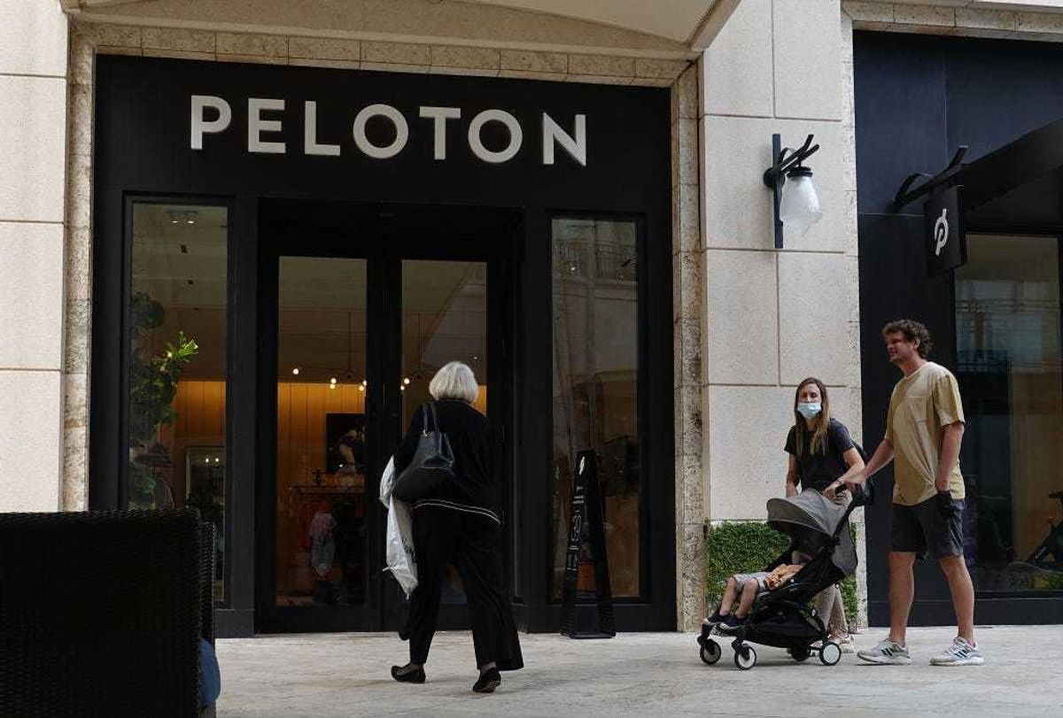 People walk past a Peloton store on January 20, 2022 in Coral Gables, Florida. Reports indicate that Peloton Interactive Inc is temporarily halting production of its bikes and treadmills after a drop in demand for the products. (Photo by Joe Raedle/Getty Images)