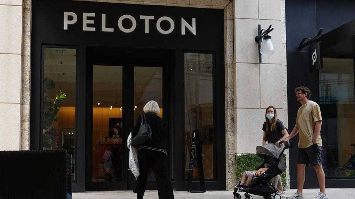 People walk past a Peloton store on January 20, 2022 in Coral Gables, Florida. Reports indicate that Peloton Interactive Inc is temporarily halting production of its bikes and treadmills after a drop in demand for the products. (Photo by Joe Raedle/Getty Images)