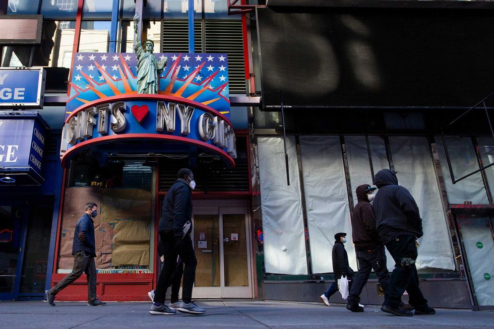 People walk past a shuttered souvenir store at Times Square on November 16, 2020 in New York. Some souvenir stores are struggling to keep afloat as tourist numbers dip due to COVID-19 pandemic, with new cases on the rise.