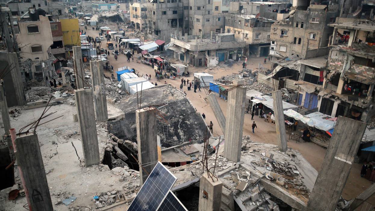 People walk past stalls selling goods amid the rubble of buildings destroyed during previous Israeli strikes, in Khan Yunis in the southern Gaza Strip.