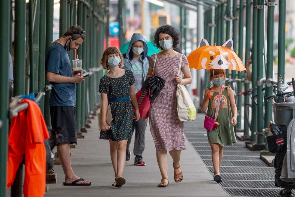 People walk under sidewalk scaffolding in Manhattan